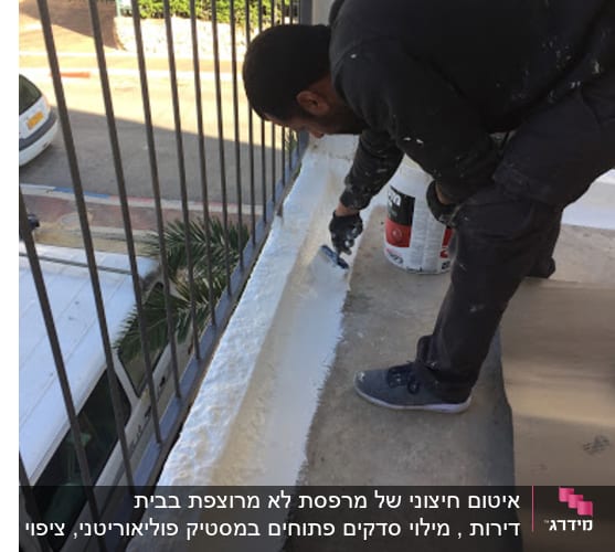אדם מורח חומר איטום על רצפת מרפסת